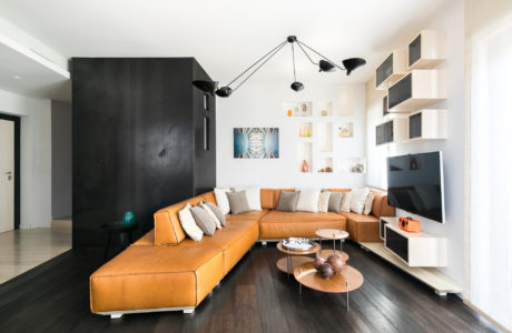 Contemporary living room with L-shaped orange sofa and sleek black wall unit.