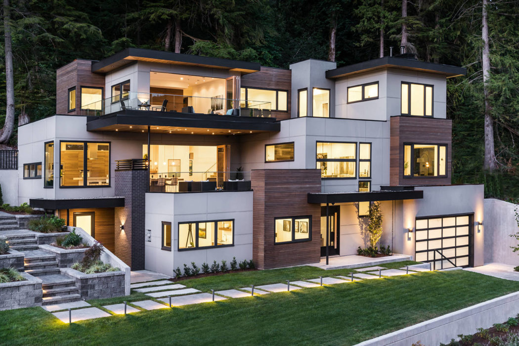Luxurious multi-level home with warm interior lighting and wood paneling at dusk.