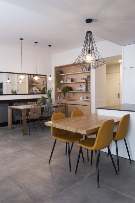 Contemporary dining space with wooden table, yellow chairs, and geometric lighting.
