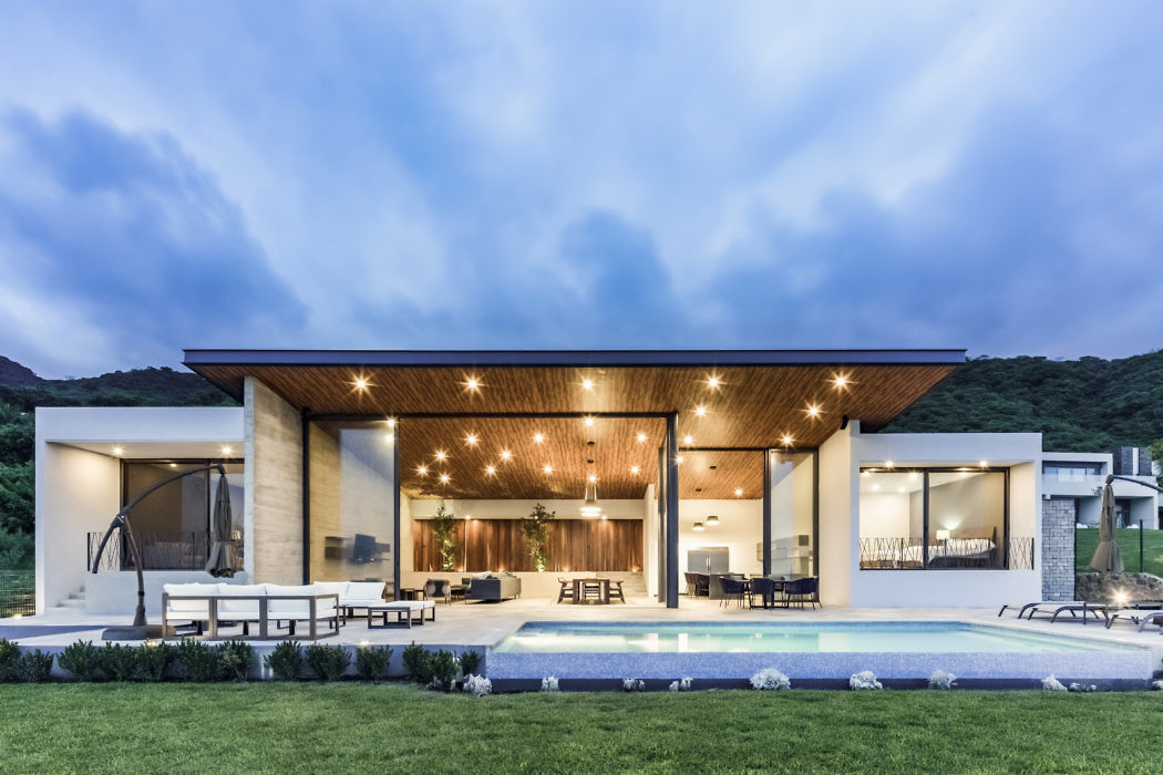 Modern house exterior at dusk with pool and patio area.