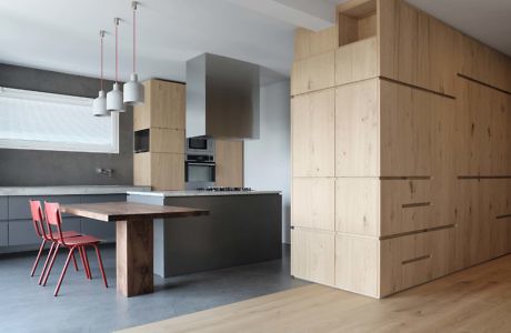 Minimalist kitchen with wooden cabinets and a pink chair.