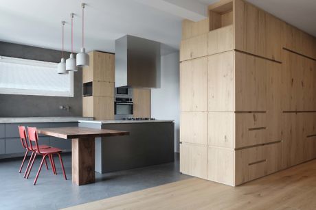 Minimalist kitchen with wooden cabinets and a pink chair.