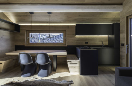 Modern kitchen with wooden walls, black cabinets, and a dining area with a view