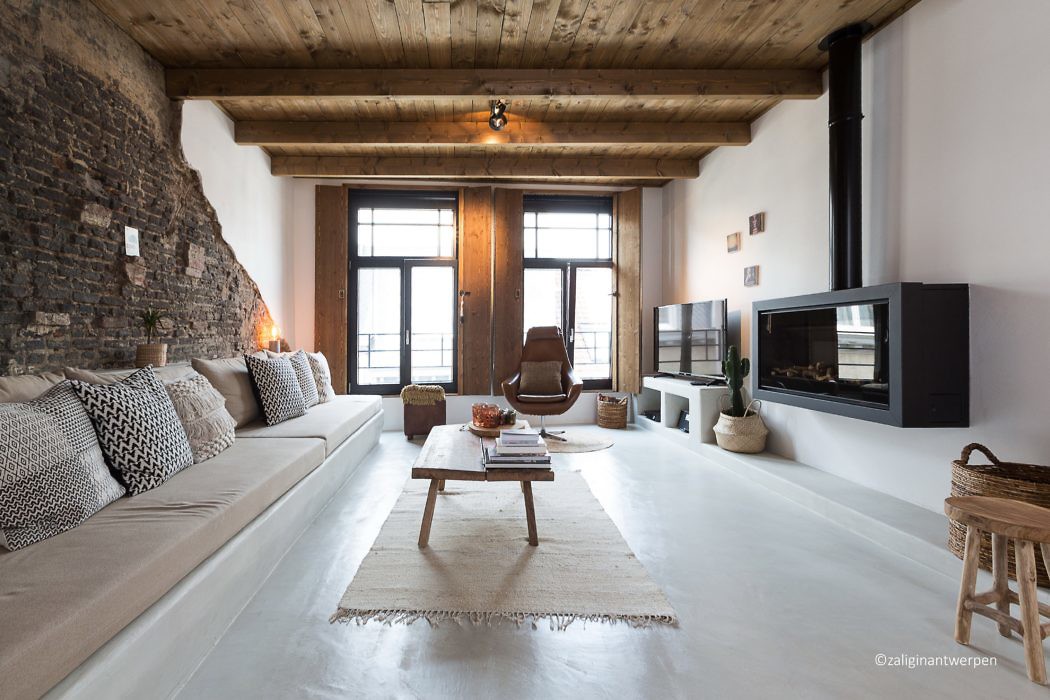 Modern living room with exposed brick, wooden beams, and a fireplace.