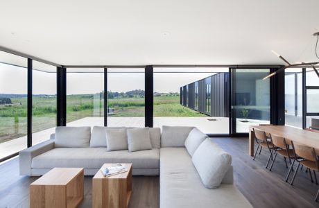 Modern living room with large windows, sectional sofa, and a wooden table, overlooking