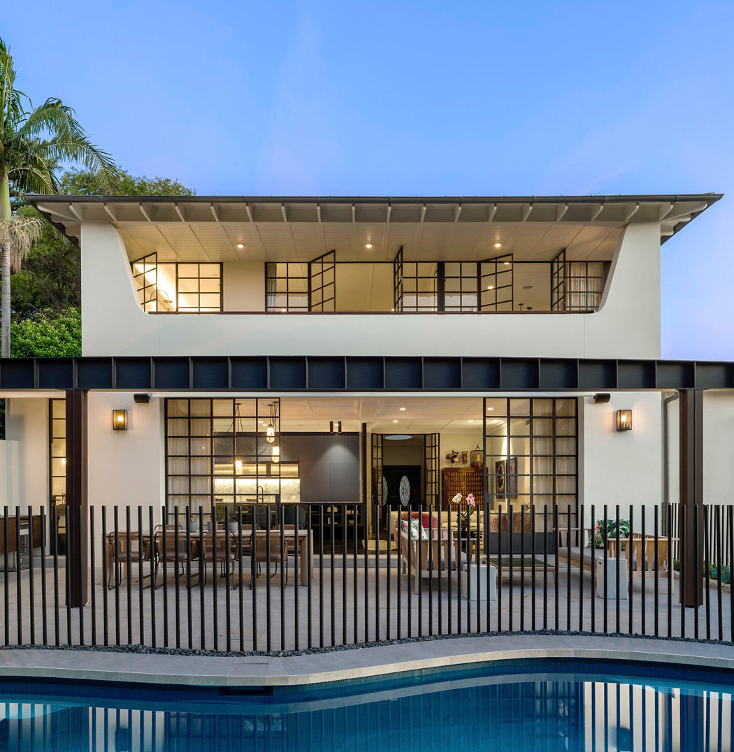 Contemporary two-story home with poolside view and distinctive overhanging roof.