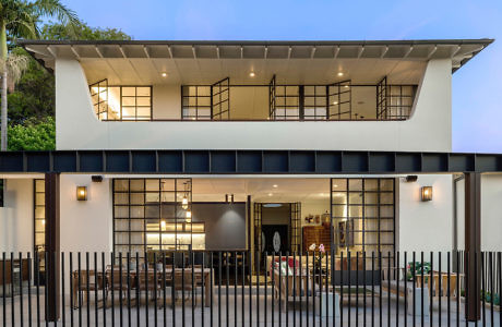 Contemporary two-story home with poolside view and distinctive overhanging roof.