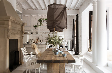 Elegant dining area with rustic table, white brick walls, and classic fireplace.