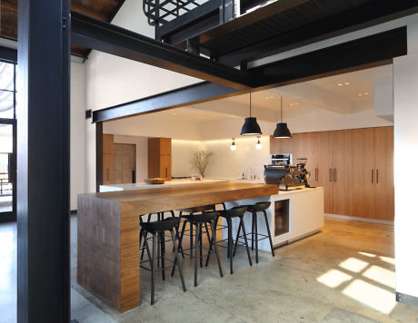 Modern kitchen interior with a wooden island, black stools, and pendant lights.