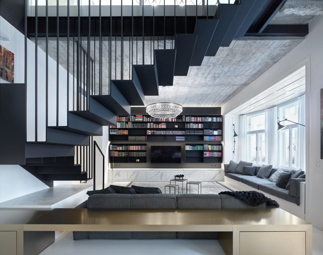 Monochrome living space with striking staircase and bookshelf wall.