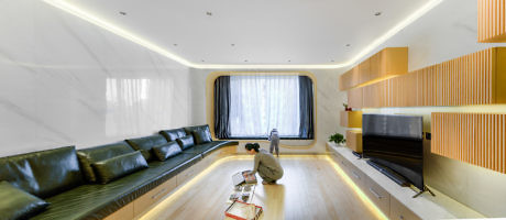 Modern living room with wooden accents, long sofa, and floor lighting.