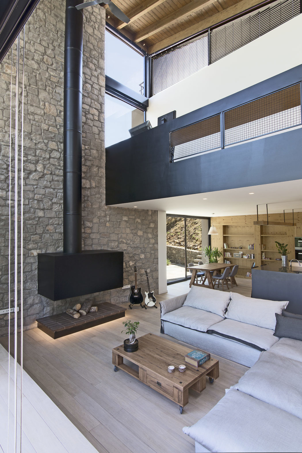 Contemporary open-plan living space with stone fireplace and mezzanine
