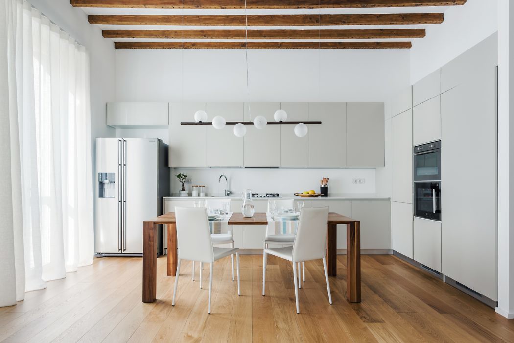 Bright minimalist kitchen with exposed wooden beams and sleek dining set.