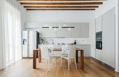 Bright minimalist kitchen with exposed wooden beams and sleek dining set.