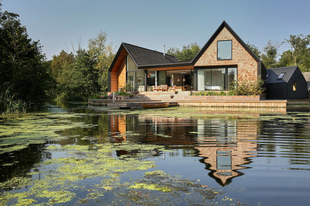 Contemporary lakeside house with large windows and a gabled roof.