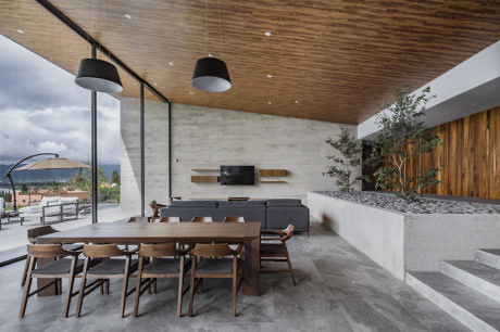 Modern outdoor dining area with wooden table, pendant lights, and concrete finishes.