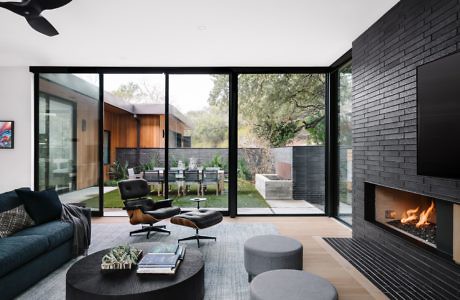 Modern living room with fireplace, large windows, and garden view.