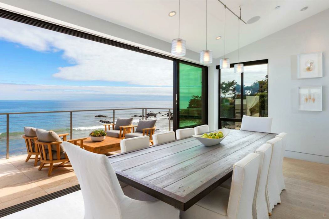 Modern dining room with ocean view through floor-to-ceiling windows.