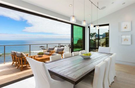 Modern dining room with ocean view through floor-to-ceiling windows.