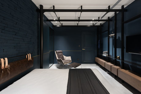 Contemporary bedroom with navy walls, black canopy bed, and sleek furniture.