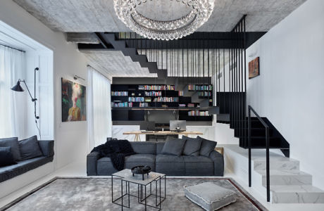 Modern living room with mezzanine, black staircase, and elegant chandelier.