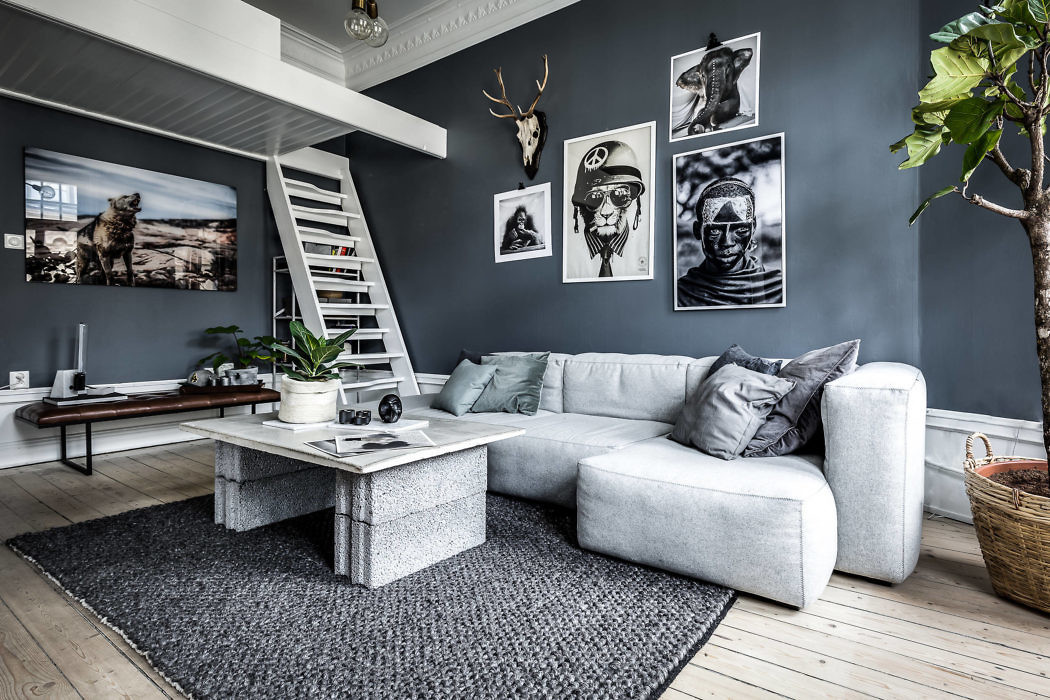 Modern living room with gray sofa, art decor, and white staircase.