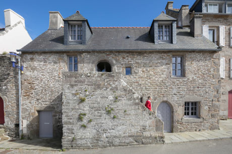 Traditional stone building with arched door and person in red.