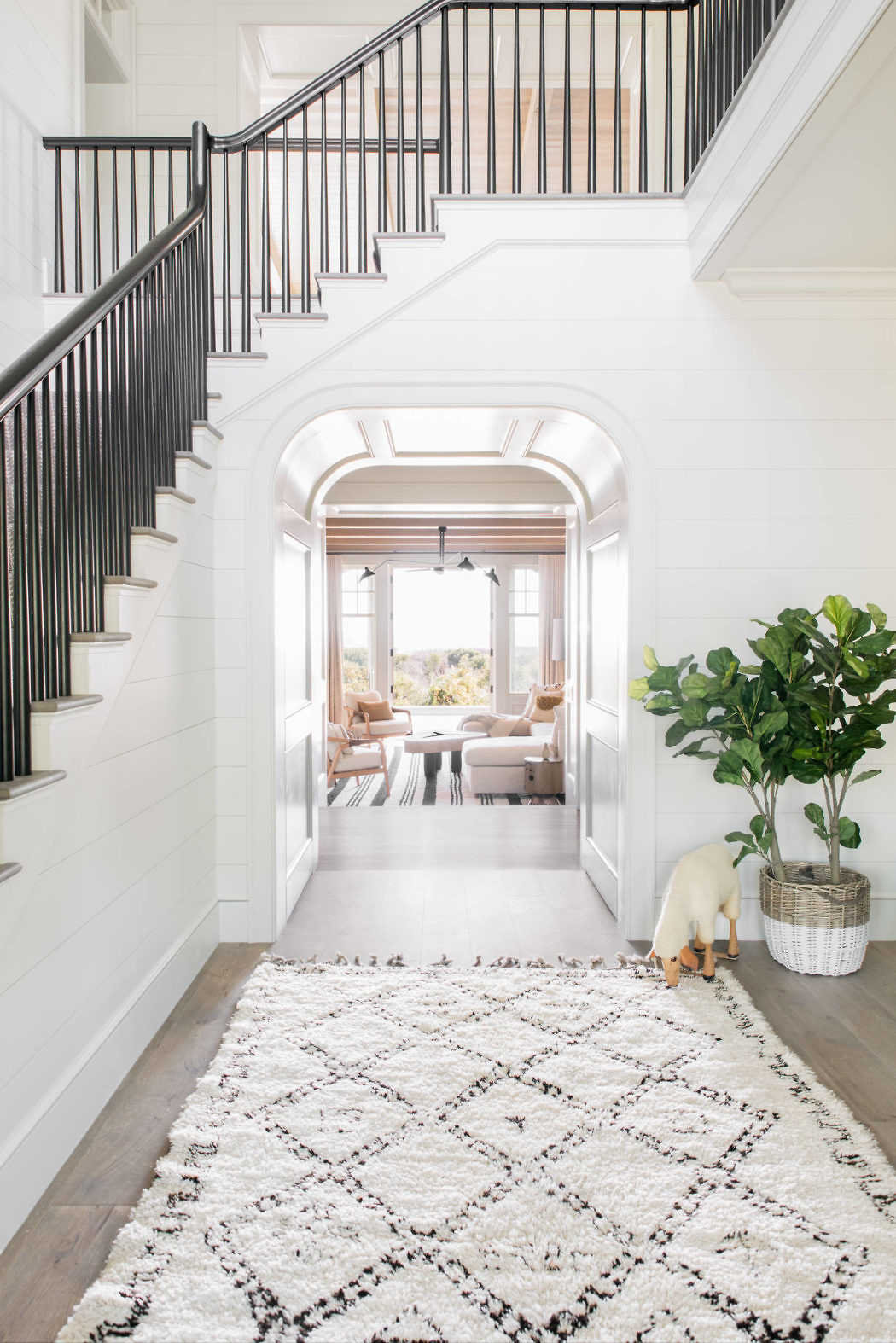 Elegant entryway with a black staircase, white walls, and a patterned