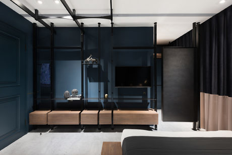 Modern bedroom with dark blue walls, wooden shelves, and black curtains.