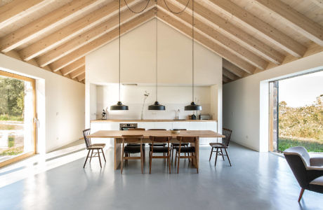 Modern kitchen interior with a dining table, wooden ceiling, and large windows.