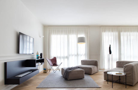 Modern living room with minimalistic furniture and sheer curtains.