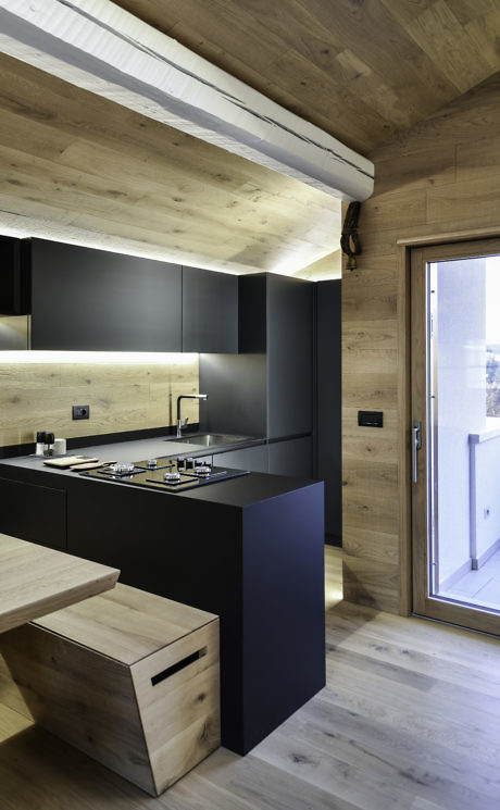 Modern kitchen with wooden ceiling and dark cabinets.