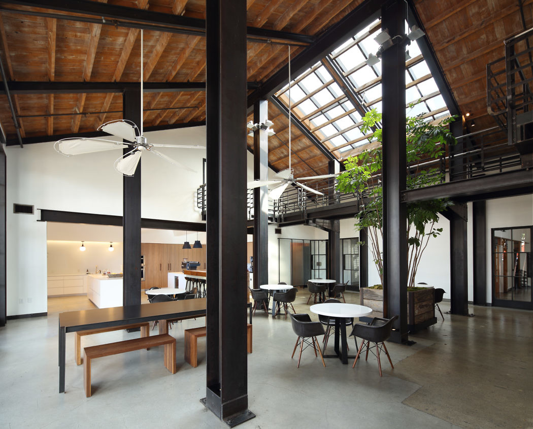 Modern industrial loft interior with skylight, exposed beams, and mixed dining furniture
