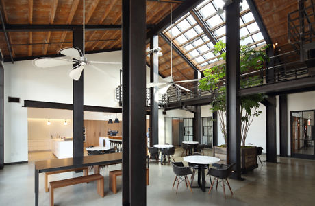 Modern industrial loft interior with skylight, exposed beams, and mixed dining furniture