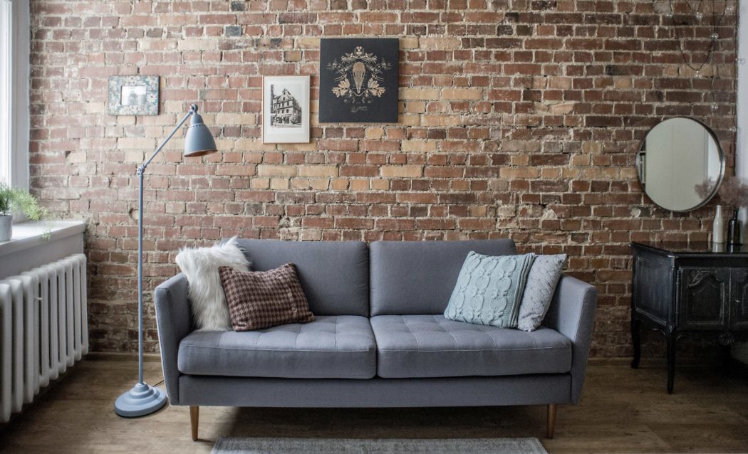 Chic living area with exposed brick wall, grey sofa, and vintage accents.
