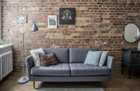 Chic living area with exposed brick wall, grey sofa, and vintage accents.