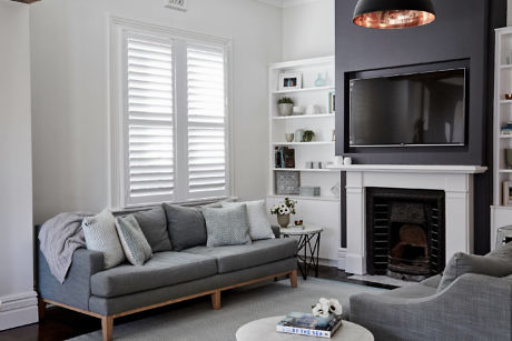 Modern living room with grey sofa, fireplace, and mounted TV.