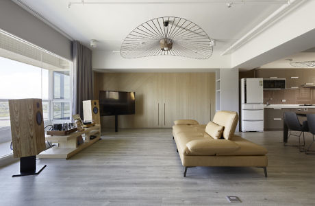 Contemporary living space with tan sofa, wooden accents, and circular ceiling fan.