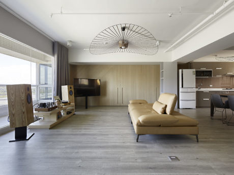 Contemporary living space with tan sofa, wooden accents, and circular ceiling fan.