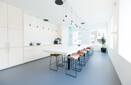 Minimalist kitchen with white cabinetry and long dining table.