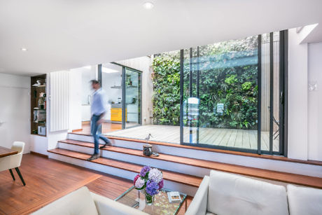 Modern living room with large windows leading to a wooden deck, a person in motion