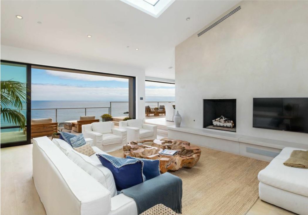 Modern living room with ocean view, white furniture, and a wooden coffee table.