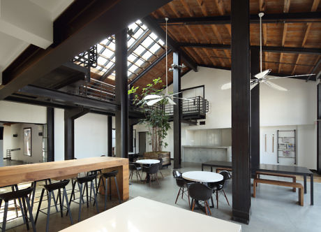 Modern loft interior with wooden beams, skylight, and minimalist furniture.
