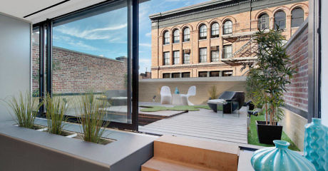 Modern terrace with garden planters, seating, and urban view.