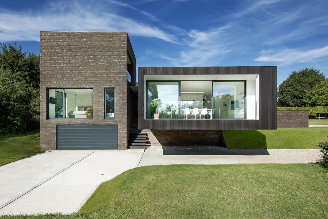 Contemporary dark brick house with large glass windows and cantilevered upper level