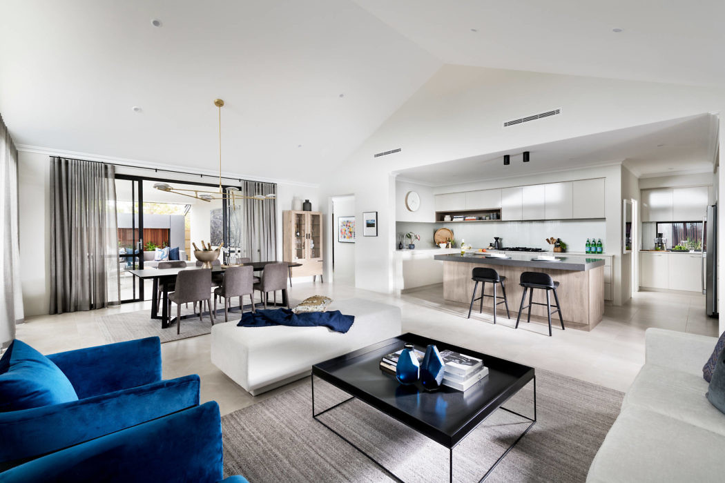 Elegant open-plan living space with sleek kitchen and vibrant blue sofas.