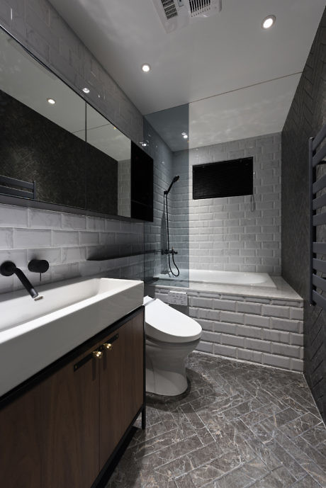 Modern bathroom with gray tiles, wood vanity, and walk-in shower.