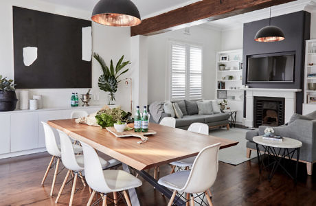 Modern dining room with a wooden table, white chairs, and a fireplace.