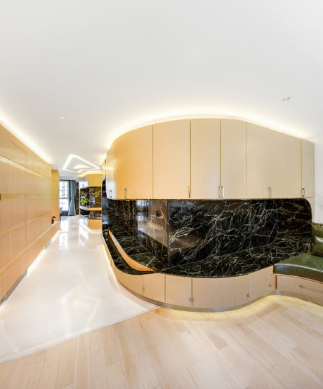Contemporary hallway with curved wooden panels and black marble accent.
