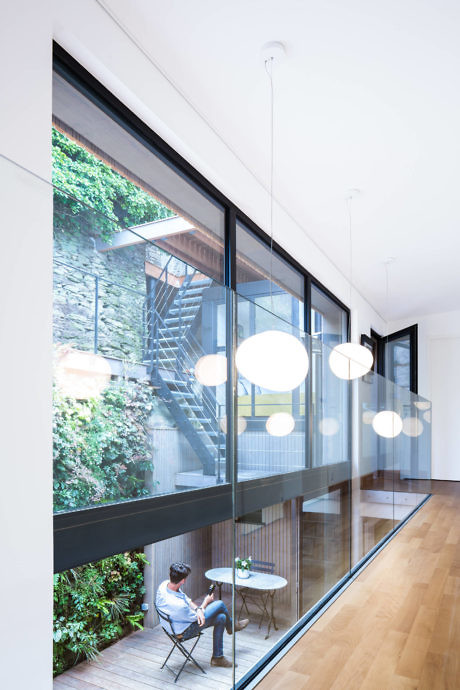 Minimalist interior with glass wall overlooking greenery and stairs.